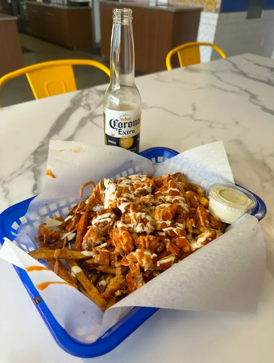 Customer photo: loaded fries drizzled with sauce and ranch in a blue basket at Wing Kings Trawood